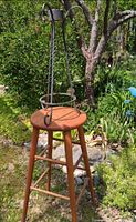 Wooden stool supporting wrought iron plant stand outdoors