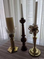 Three candlesticks with candles, hurricane cup visible