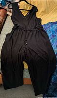 Full view of black sleeveless romper on hanger