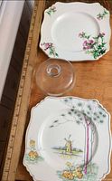 Both square Royal Winton plates and glass cheese cover on table with ruler for scale