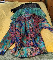 All three blouses laid out on bed showing overall colors and patterns