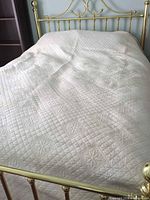 Quilt spread on metal bed frame, overall view shows color and pattern