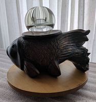 Carved wood fish candleholder with glass orb displayed on top