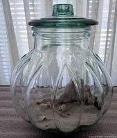 Overall view of ribbed pumpkin-shaped aqua glass jar with lid and contents