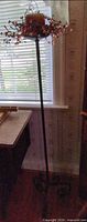 Full view of wrought iron floor candle stand with candle and garland