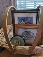Wicker basket containing three framed cat prints