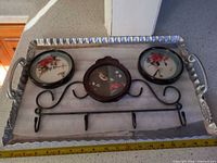 Tray containing three round artworks and apple rack displayed with tape for scale