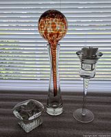 Front view of square votive holder, bud vase with Kitras globe inserted, and stemmed votive holder with star candle