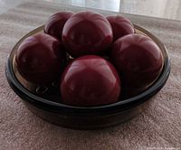 Smoked glass bowl filled with six burgundy spheres