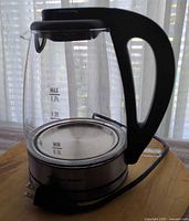 Full view of glass kettle showing handle, spout, water level marks, corded base