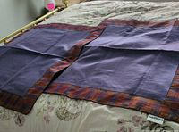 Pair of purple center pillow shams with checked borders laid flat