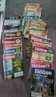 Stacked magazines spread on carpet showing covers and quantity