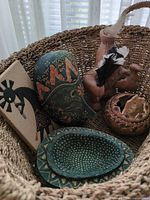 All items grouped in basket showcasing mask, figurine, gourd and plaque