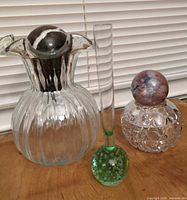 Group shot of ribbed glass vase, bud vase with green bubble base, cut crystal perfume bottle with multicolor stopper, and black marble sphere