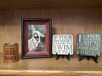 All items on shelf: coin bank, framed donkey photo, two coasters on stands