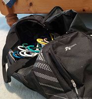 Open Oakley duffel showing assorted coloured plastic hangers inside main compartment