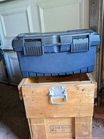Plastic toolbox resting on wooden crate, showing overall lot