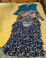 Three tops laid out: turquoise tie-dye, multicolor print, blue dot ruffle