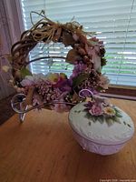 Porcelain box, floral wreath, and stand displayed together