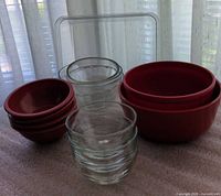 Group shot of red plastic bowls, two clear glass bowls and square clear lid
