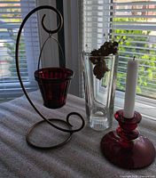All items grouped: red candlestick with candle, hanging votive on stand, clear vase