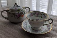 Teacup on saucer beside lidded sugar bowl