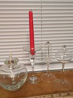 Group shot of three glass oil lamps and glass candle holder with red taper