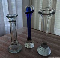 Front view of three handblown glass bud vases displaying colors and shapes