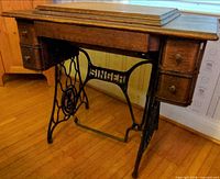 Front view of Singer wood cabinet on cast iron treadle frame, four drawers visible