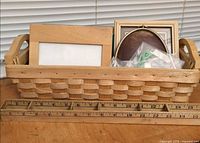 Basket holding several frames including light wood, brass oval, brown wood, others with ruler for scale
