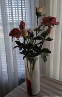 Full view of vase standing on table with artificial roses