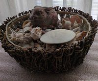Twig bowl filled with seashells and sand dollar, rabbit oil lamp visible