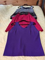 All three sleeveless tops laid out on bed