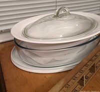 Both pieces stacked: ceramic bowl with glass lid sitting atop glass casserole with white lid beneath