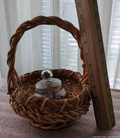 Wicker basket with handle, glass candy dish inside, ruler for scale