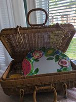 Open wicker suitcase basket showing plate and candle inside