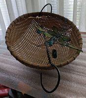 Overview of woven basket with stained glass dragonfly and metal hook hanger displayed inside