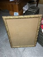 Full view of rectangular ornate gold frame with glass and backing board
