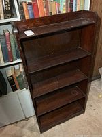 front view of dark wood bookcase showing four shelves and wear