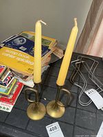 Pair of brass bugle-style candlesticks with yellow candles on tabletop