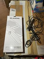 Front of sealed M-Audio EX-P pedal box alongside one vintage microphone with cable