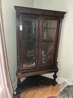 Full view of cabinet showing double glass doors, top crown molding, and lower open shelf