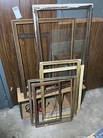 Stack of assorted empty frames leaning against wall