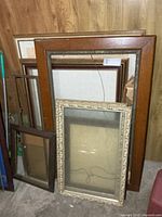 Stack of assorted wooden and ornate frames leaning against wall