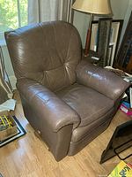 Front angled view of brown leather La-Z-Boy recliner showing seat, arms, and lever
