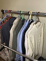 Rack with six collared shirts and a cable-knit sweater