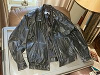 Front view of black leather jacket laid flat showing overall style and condition