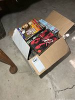 Open cardboard box filled with VHS tapes and DVDs