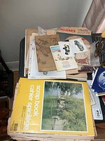 Pile showing yellow scrapbook, brown scrapbook, assorted papers and postcards