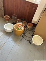 Group of planters, pots, and metal stands on floor